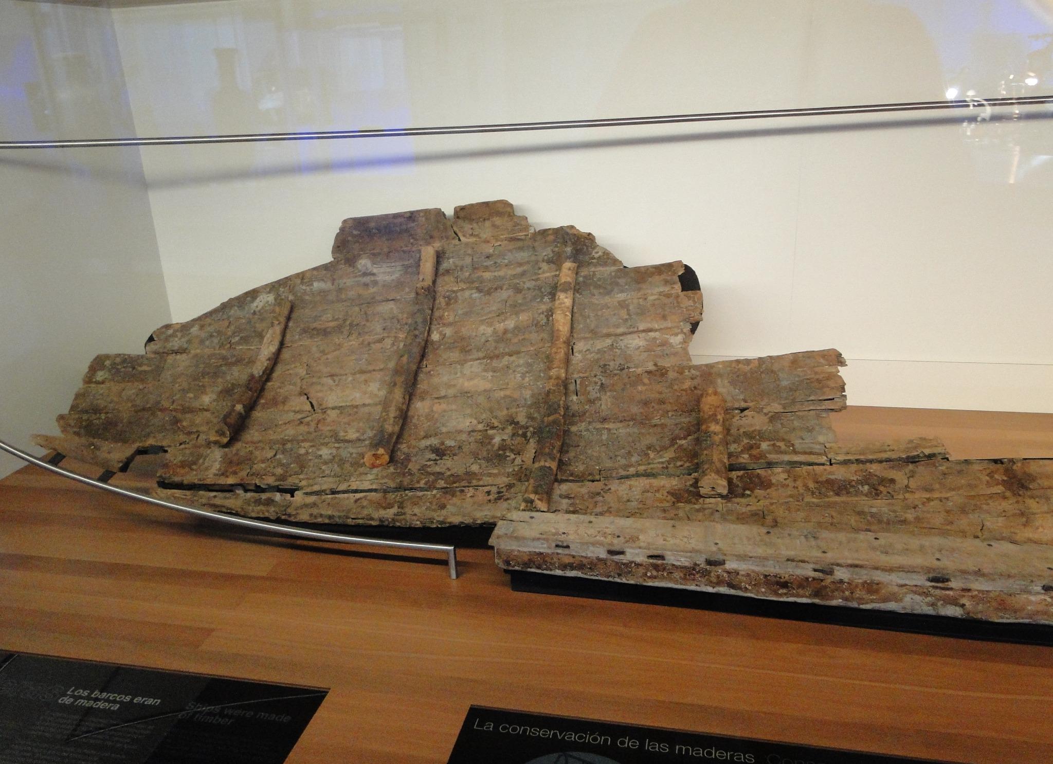 Roman shipwreck remains displayed in a museum case with informational panels